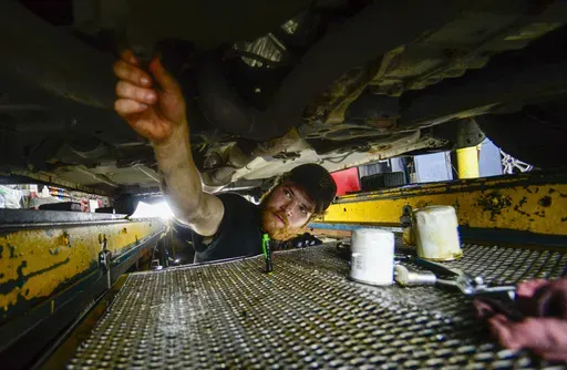 Ian Frank, a pit technician at Stop & Go on Putney Road in Brattleboro, Vt., changes the oil on a vehicle on July 15, 2024. (Kristopher Radder/The Brattleboro Reformer via AP, File)