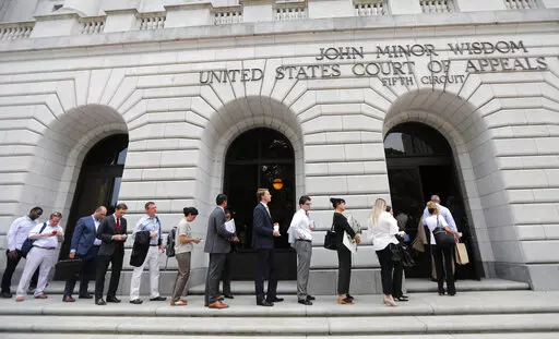In this Tuesday, July 9, 2019 file photo, People wait in line to enter the 5th Circuit Court of Appeals to sit in overflow rooms to hear arguments in New Orleans.  President Joe Biden's requirement that all federal employees be vaccinated against COVID-19 is awaiting judgment from a federal appeals court after arguments in New Orleans. An administration attorney told the court Tuesday, March 8, 2022, that a federal judge in Texas overstepped his authority when he blocked the mandate.   (AP Photo