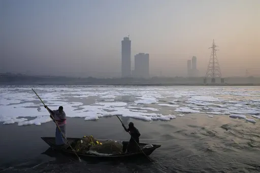 Fishermen row their boat amidst morning smog in the river Yamuna as toxic foam floats in the river ahead of Diwali festival in New Delhi, India, Tuesday, Oct. 29, 2024. (AP Photo/Manish Swarup)