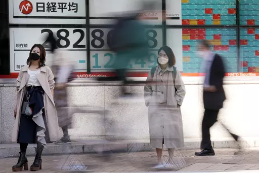 People wait for crossing a street in front of an electronic stock board showing Japan's Nikkei 225 index at a securities firm Thursday, April 27, 2023, in Tokyo. Asian shares mostly fell Thursday, echoing the drop on Wall Street, as worries about the U.S. banking sector and inflationary pressures weighed on investor sentiment.(AP Photo/Eugene Hoshiko)
