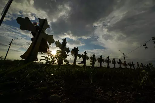 Vehicles pass crosses placed to honor the victims of the shootings at Robb Elementary School, Thursday, Aug. 25, 2022, in Uvalde, Texas. The Texas Department of Public Safety has fired an officer who was at the scene of the school massacre and becomes the first member of the state police force to lose their job in the fallout over the hesitant response to the May attack. (AP Photo/Eric Gay, File)