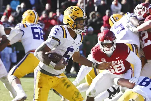 LSU quarterback Jayden Daniels (5) tries to find a hole in the Arkansas defense as he runs the ball during the second half of an NCAA college football game Saturday, Nov. 12, 2022, in Fayetteville, Ark. (AP Photo/Michael Woods)