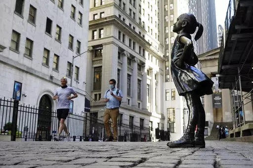 In this June 16, 2021, photo, the "Fearless Girl" statue faces the New York Stock Exchange. The 4-foot bronze "Fearless Girl" statue that was installed opposite New York City's Charging Bull in 2017 will remain in its current spot opposite the New York Stock Exchange at least until early 2023 while city officials wrestle with a permanent disposition for the popular symbol of female empowerment, a city board decided Monday, April 11, 2022. (AP Photo/Richard Drew, File)