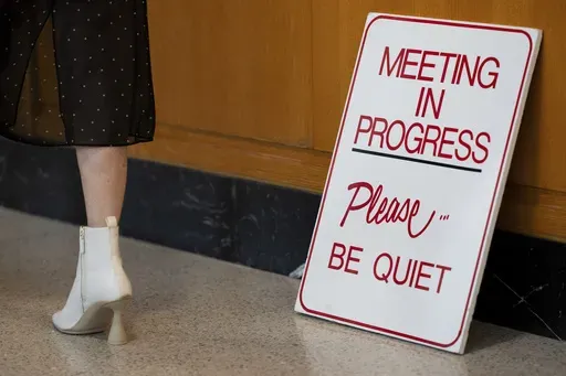 A person walks by a sign for a meeting in progress at the Oregon state Capitol on Wednesday, Dec. 11, 2024, in Salem, Ore. (AP Photo/Jenny Kane)