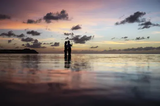 Tourists watch the sun set along a popular beach in Tamuning, Guam, May 6, 2019. (AP Photo/David Goldman, File)