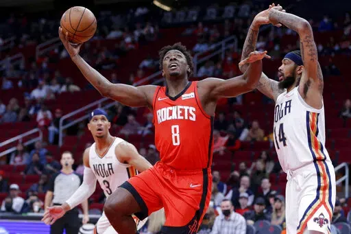 Houston Rockets forward Jae'Sean Tate (8) shoots between New Orleans Pelicans guard Josh Hart (3) and forward Brandon Ingram (14) during the first half of an NBA basketball game Sunday, Feb. 6, 2022, in Houston. (AP Photo/Michael Wyke)