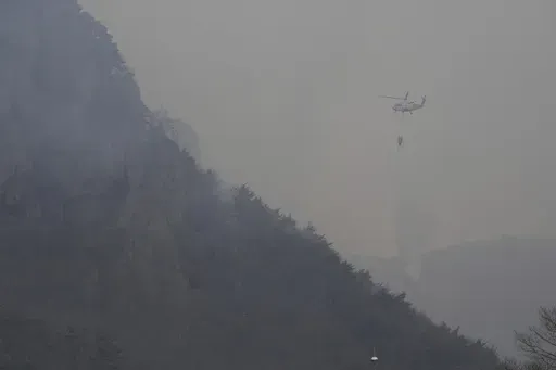A helicopter dumps water on a mountain after a wildfire broke out in Cheongsong, South Korea, Thursday, March 27, 2025. (AP Photo/Ahn Young-joon)