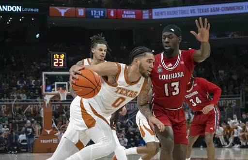 Texas forward Timmy Allen (0) drives the ball against Louisiana-Lafayette guard Greg Williams, Jr. (13) during the first half of an NCAA college basketball game, Wednesday, Dec. 21, 2022, in Austin, Texas. (AP Photo/Michael Thomas)