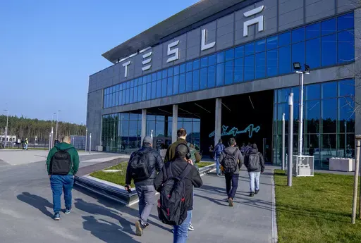 People walk to the Tesla Gigafactory for electric cars in Gruenheide near Berlin, Germany,March 13, 2024. After reporting dismal first-quarter sales, Tesla is planning to lay off about a tenth of its workforce as it tries to cut costs, multiple media outlets reported Monday. (AP Photo/Ebrahim Noroozi, File)