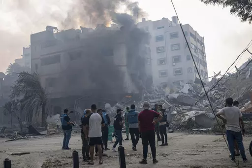 Journalists observe as Palestinians inspect the rubble of a building after it was struck by an Israeli airstrike, in Gaza City, Sunday, Oct. 8, 2023. Journalists reporting in Gaza need to worry about basic survival for themselves and their families in addition to getting out the story of a besieged population. (AP Photo/Fatima Shbair, File)