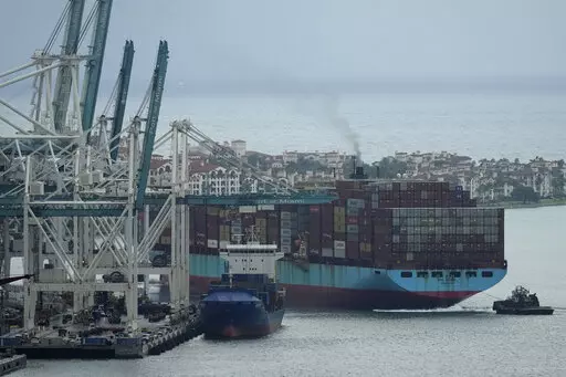 Tugboats guide the Axel Maersk container ship as it arrives into port, Oct. 21, 2021, in Miami. The marine shipping industry is facing new regulations to address carbon pollution. Its trade groups have been seeking exemptions for pollution emitted during voyages on rough seas. (AP Photo/Rebecca Blackwell, File)