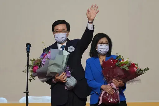 John Lee, former No. 2 official in Hong Kong and the only candidate for the city's top job, celebrates with his wife after declaring his victory in the chief executive election of Hong Kong in Hong Kong, Sunday, May 8, 2022. Lee was elected as Hong Kong's next leader Sunday by an election committee comprised of nearly 1,500 largely pro-Beijing members. (AP Photo/Kin Cheung)