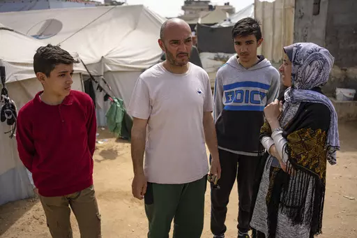 Heba al-Haddad, right, and her family displaced from Gaza City, stand in a makeshift tent camp in Rafah, southern Gaza, Friday, March 29, 2024. Al-Haddad was forced out of her home in Gaza City on March 21 when Israeli troops stormed her apartment and ordered her and her family to leave for the south. Amid fighting that has engulfed the area since Israel raided Shifa Hospital, witnesses say troops have been pushing residents out of nearby neighbourhoods. (AP Photo/Fatima Shbair)
