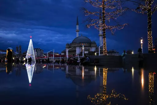 Pedestrians walk past a Christmas tree next to Taksim mosque at Taksim square in Istanbul, Turkey, Friday, Dec. 10, 2021. (AP Photo/Francisco Seco)