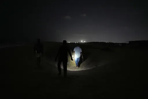 A forest official walks with volunteers to search for olive ridley sea turtle eggs on Marina Beach in Chennai, India, Thursday, March 13, 2025. (AP Photo/Mahesh Kumar A.)