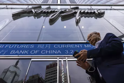 A pedestrian passes by the Hong Kong Stock Exchange electronic screen in Hong Kong, Tuesday, April 18, 2023. Asian shares were trading mixed Tuesday as pessimism about global uncertainties remained even as China reported a better-than-expected economic growth data. (AP Photo/Louise Delmotte)