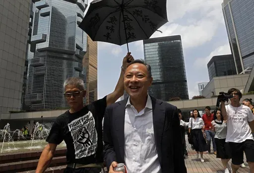 Occupy Central leader Benny Tai, center, is accompanied by a supporter who raises an umbrella as he leaves high court in Hong Kong, on Aug. 15, 2019. (AP Photo/Vincent Yu, File)