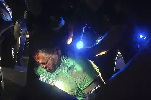This image from video from Louisiana state police state trooper Dakota DeMoss' body-worn camera, shows troopers holding up Ronald Greene before paramedics arrived on May 10, 2019, outside of Monroe, La. On Monday, Nov. 14, 2022, a Louisiana grand jury began hearing evidence in the deadly 2019 arrest of Greene, long-awaited testimony that will determine whether state charges are brought against the white troopers seen on body-camera video stunning, striking and dragging the Black motorist by his 