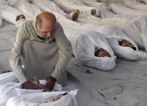 This Aug. 21, 2013 file citizen journalism image provided by the anti-government Media Office Of Douma City which has been authenticated based on its contents and other AP reporting, shows a Syrian man mourning over a dead body after an alleged poisonous gas attack fired by government forces, according to activists, in Douma town, Damascus, Syria. Syria denies ever using chemical weapons during the war and says it eliminated its chemical arsenal under a 2013 agreement brokered by the U.S. and ke