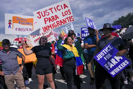 People carry signs that read in Spanish, "Justice for Immigrants" and "We are humans" as hundreds gather to protest peacefully against Florida Senate bill 1718, which imposes restrictions on undocumented immigrants, Thursday, June 1, 2023, in Immokalee, Fla., an area known for its tomato-growing. Across Florida Thursday, workers didn't show up at construction sites, and tomato fields, while scores of restaurants and small businesses never opened their doors to protest the new state law. (AP Phot