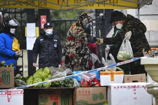In this photo released by Xinhua News Agency, residents buy produce from a temporary market set up at the entrance of a quarantined residential area in Xi'an in northwestern China's Shaanxi Province on Dec. 25, 2021. Xi'an, which is about 1,000 kilometers (600 miles) southwest of Beijing, reported more than 300 new cases over the weekend, a sharp rise from previous days. The city of 13 million people has been locked down, with only one person per household allowed out every two days to shop for 