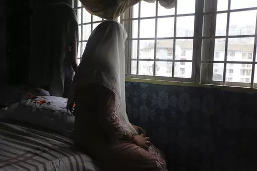 Rohingya child bride, B, age 14, sits on a bed in an apartment in Kuala Lumpur, Malaysia, on Oct. 4, 2023. B came to Malaysia in 2023 to marry an older man. Her husband wants her to get pregnant, but she says she doesn't feel ready. "I still feel like a girl." Deteriorating conditions in Myanmar and in neighboring Bangladesh’s refugee camps are driving scores of underage Rohingya girls to Malaysia for arranged marriages with Rohingya men who frequently abuse them, The Associated Press found in