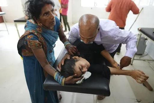 A father tries to calm his daughter suffering from a heat-related ailment as she is brought to the government district hospital in Ballia, Uttar Pradesh state, India, June 19, 2023. The official number of heat deaths listed in government reports barely scratches the surface of the true toll and that's affecting future preparations for similar swelters, according to public health experts. (AP Photo/Rajesh Kumar Singh, File)