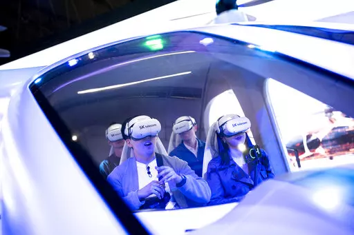 Visitors test a SK Telecom VR flight simulator during the Mobile World Congress 2023 in Barcelona, Spain, Monday, Feb. 27, 2023. The four-day show kicks off Monday in a vast Barcelona conference center. It's the world's biggest and most influential meeting for the mobile tech industry. (AP Photo/Joan Mateu Parra)