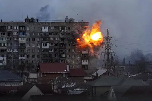 An explosion is seen in an apartment building after Russian's army tank fires in Mariupol, Ukraine, Friday, March 11, 2022. (AP Photo/Evgeniy Maloletka, File)