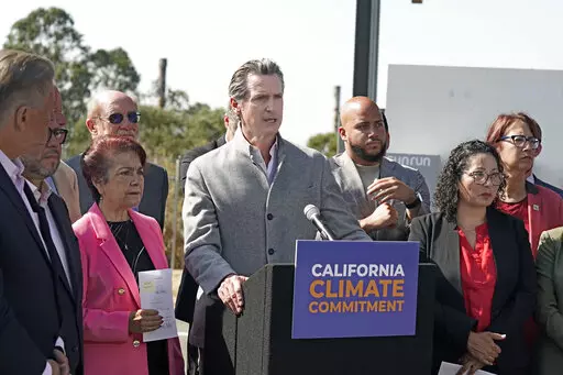 Gov. Gavin Newsom, center, is flanked by state lawmakers while discussing the package of legislation he signed that accelerates the climate goals of the nation's most populous state, at Mare Island in Vallejo, Calif., Friday, Sept. 16, 2022. Newsom opposes Proposition 30, which would raise taxes on people making more that $2 million to pay for electric vehicle infrastructure and firefight resources. (AP Photo/Rich Pedroncelli, File)