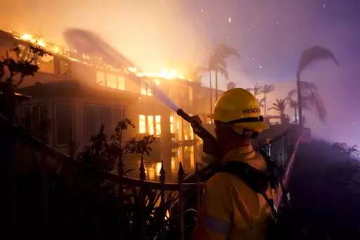 A firefighter works to put at a structure burning during a wildfire Wednesday, May 11, 2022, in Laguna Niguel, Calif. (AP Photo/Marcio J. Sanchez)