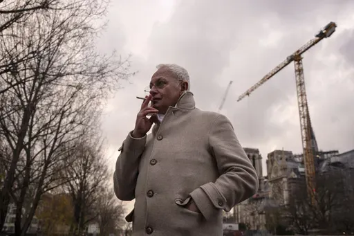 Notre-Dame de Paris cathedral chief architect Philippe Villeneuve smokes a cigarette by the cathedral during an interview with Associated Press, Tuesday, Dec. 3, 2024 in Paris. (AP Photo/Louise Delmotte)