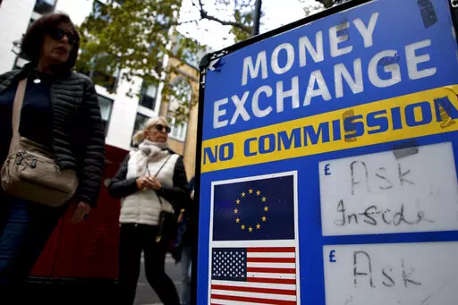 People walk past a currency exchange bureau in London, Monday, Sept. 26, 2022. The pound today slumped to its lowest level against the dollar since 1971, after the Chancellor hinted more tax cuts would follow those he announced last week. The pound dipped as low as $1.0349 per U.S. dollar early Monday but then rebounded to $1.0671, down 2.3%. (AP Photo/David Cliff)