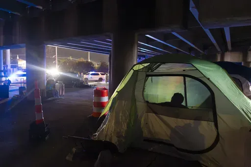 Homeless people wake up in the early morning as Louisiana State Troopers pull up underneath the Pontchartrain Expressway in downtown New Orleans on Wednesday, Jan. 15, 2025. (Chris Granger /The Times-Picayune/The New Orleans Advocate via AP)