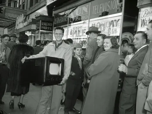 Phil Bustos of Trinidad, Colo., displays the television set he bought for $29 at a Washington's Birthday sale in Washington, D.C., Feb. 22, 1954. Other bargain hunters waited to get into the packed store during the annual holiday sale. (AP Photo, File)