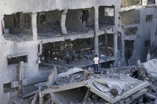 Palestinians inspect the rubble of destroyed building of Muharib family killed in the Israeli bombardment of the Gaza Strip in Nusseirat refugee camp, central Gaza Strip, Thursday, Nov. 23, 2023. (AP Photo/Adel Hana)