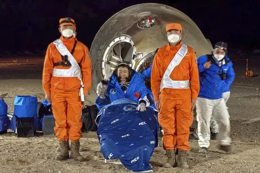In this photo released by Xinhua News Agency, astronaut Chen Dong waves as he sits outside the re-entry capsule of the Shenzhou-14 manned space mission after it lands successfully at the Dongfeng landing site in northern China's Inner Mongolia Autonomous Region, Sunday, Dec. 4, 2022. Three Chinese astronauts landed in a northern desert on Sunday after six months working to complete construction of the Tiangong station, a symbol of the country's ambitious space program, state TV reported. (Li Gan