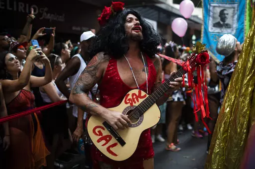 Leandro Vieira, carnival director of the Imperatriz Leopoldinense samba school, plays the guitar and wears a costume in honor of late Brazilian singer Gal Costa, during the pre-carnival parade by the Cordao do Boitata block in Rio de Janeiro, Brazil, Sunday, Feb. 12, 2023. Vieira's job includes helping pick the samba school's theme for the year, calling shots on the material for costumes and often choosing who will feature on the top of majestic floats. (AP Photo/Bruna Prado)