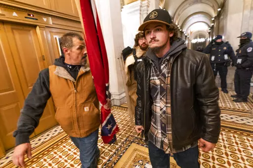 Insurrectionists loyal to President Donald Trump, including Kevin Seefried, left, walk on a hallway after a confrontation with Capitol Police officers outside the Senate Chamber inside the Capitol, Jan. 6, 2021 in Washington. A federal trial is scheduled to start on Monday, June 13, for Seefried and his son Hunter who have been charged with storming the U.S. Capitol together. (AP Photo/Manuel Balce Ceneta, File)