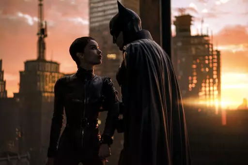 This image released by Warner Bros. Pictures shows Zoe Kravitz, left, and Robert Pattinson in a scene from "The Batman."  “The Batman” is still going strong three weeks into its theatrical run, with a tight grip on the top spot at the box office. Robert Pattinson’s debut as the Dark Knight earned an additional $36.8 million over the weekend, according to studio estimates Sunday, March 20, 2022. It also slid past the $300 million mark ahead of projections. (Jonathan Olley/Warner Bros. Pictu