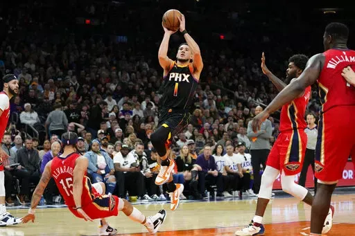 Phoenix Suns guard Devin Booker (1) shoots as New Orleans Pelicans guard Jose Alvarado (15) falls during the second half of an NBA basketball game, Saturday, Dec. 17, 2022, in Phoenix. (AP Photo/Matt York)