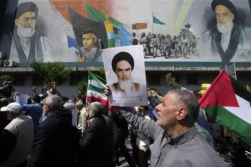 Iranian worshippers walk past a mural showing the late revolutionary founder Ayatollah Khomeini, right, Supreme Leader Ayatollah Ali Khamenei, left, and Basij paramilitary force, as they hold posters of Ayatollah Khomeini and Iranian and Palestinian flags in an anti-Israeli gathering after Friday prayers in Tehran, Iran, April 19, 2024. This month's unprecedented direct attacks between Iran and Israel are revealing deeper insights into both militaries. Experts say Friday's apparent precision str