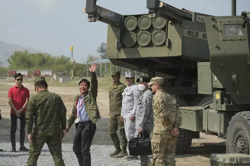 Philippine President Ferdinand Marcos Jr. waves beside a U.S. M142 High Mobility Artillery Rocket System (HIMARS) during a Combined Joint Littoral Live Fire Exercise at the joint military exercise called "Balikatan," Tagalog for shoulder-to-shoulder in a Naval station in Zambales province, northern Philippines on Wednesday, April 26, 2023. The long-time treaty allies are holding their largest joint military exercises that are part of a show of American firepower that has alarmed China. (AP Photo
