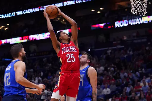 New Orleans Pelicans guard Trey Murphy III (25) goes to the basket between Dallas Mavericks forward Maxi Kleber (42) and guard Luka Doncic (77) in the second half of an NBA basketball game in New Orleans, Tuesday, Oct. 25, 2022. The Pelicans won 113-111. (AP Photo/Gerald Herbert)