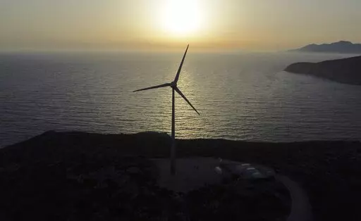 The sun sets behind a wind turbine on the Aegean Sea island of Tilos, southeastern Greece, Monday, May 9, 2022. When deciding where to test green tech, Greek policymakers picked the remotest point on the map, tiny Tilos. Providing electricity and basic services, and even access by ferry is all a challenge for this island of just 500 year-round inhabitants. It's latest mission: Dealing with plastic. (AP Photo/Thanassis Stavrakis)