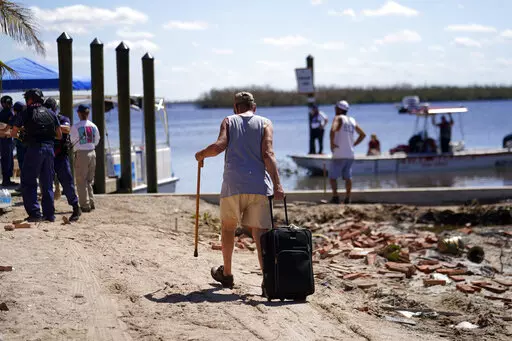 Residents who rode out the storm arrive at a dock to evacuate by boat in the aftermath of Hurricane Ian, on Pine Island in Florida's Lee County, Sunday, Oct. 2, 2022. The only bridge to the island is heavily damaged so it can only be reached by boat or air. (AP Photo/Gerald Herbert)
