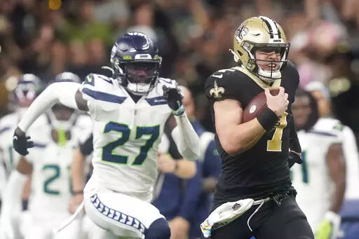 New Orleans Saints' Taysom Hill heads to the end zone for a 60 yard rushing touchdown as Seattle Seahawks' Tariq Woolen pursues during an NFL football game in New Orleans, Sunday, Oct. 9, 2022. (AP Photo/Gerald Herbert)