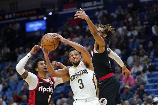 New Orleans Pelicans guard CJ McCollum (3) goes to the basket between Portland Trail Blazers guard Keon Johnson (6) and forward Greg Brown III in the second half of an NBA basketball game in New Orleans, Thursday, April 7, 2022. (AP Photo/Gerald Herbert)